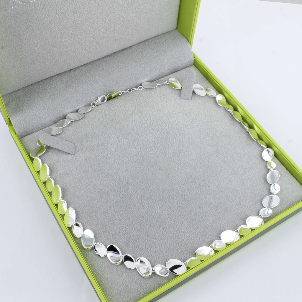 A shiny sterling silver necklace comprised of high shine oval discs finished with a lobster clasp and an extender chain.