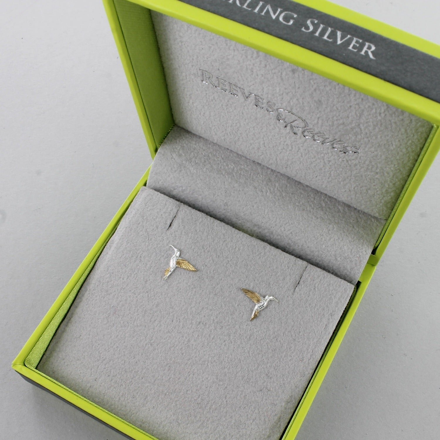 A pair of sterling silver Hummingbird stud earrings with 18ct gold plating and shown in a Reeves & Reeves gift box.