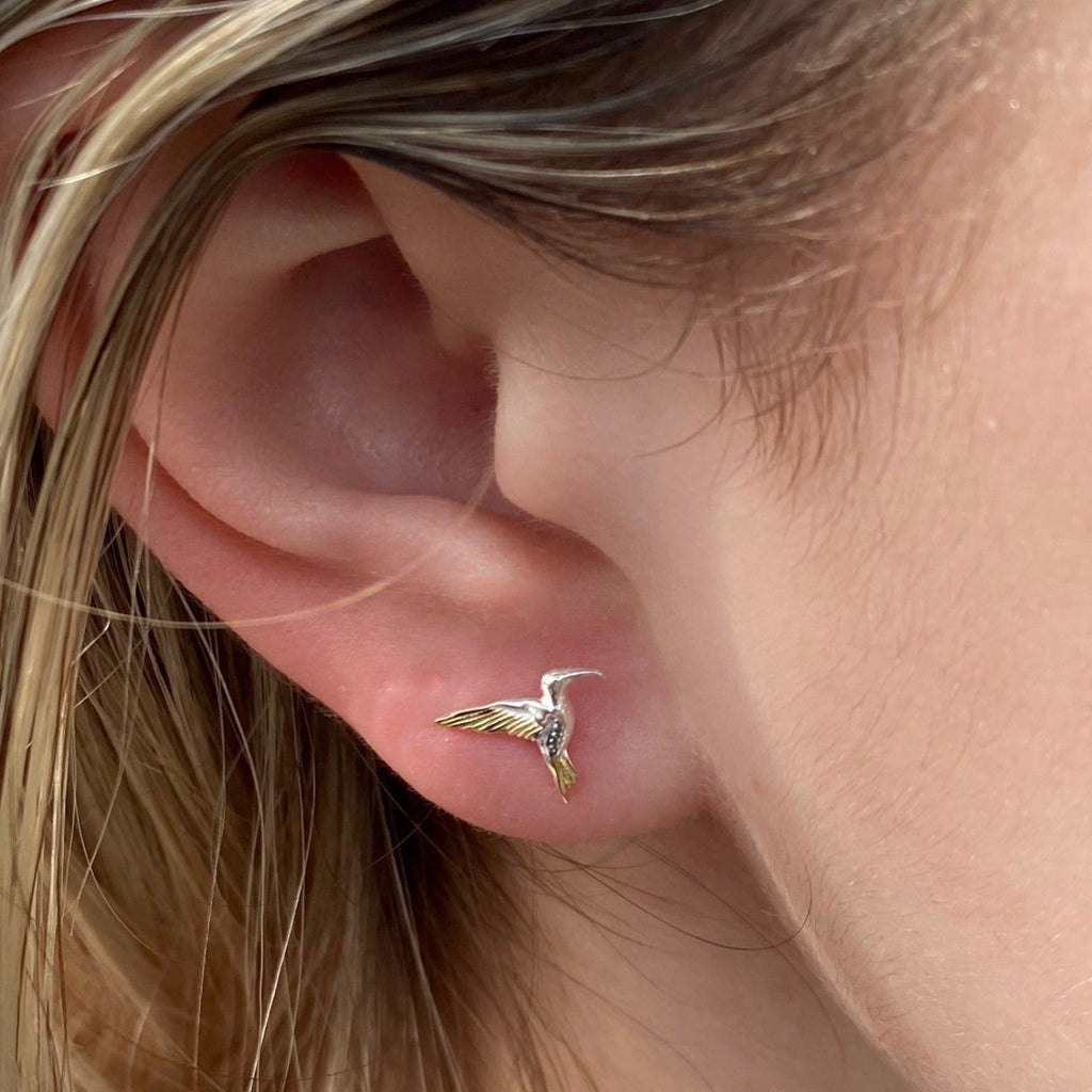 A sterling silver Hummingbird stud earring with 18ct gold plating, shown in a ladies ear.