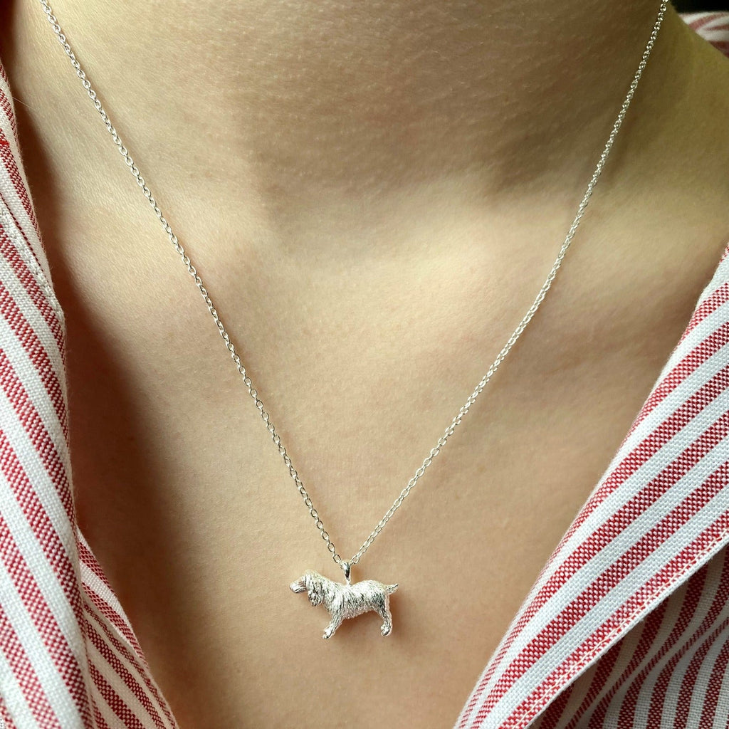 A Silver Spaniel Necklace hung on a silver chain and worn on a models neck.