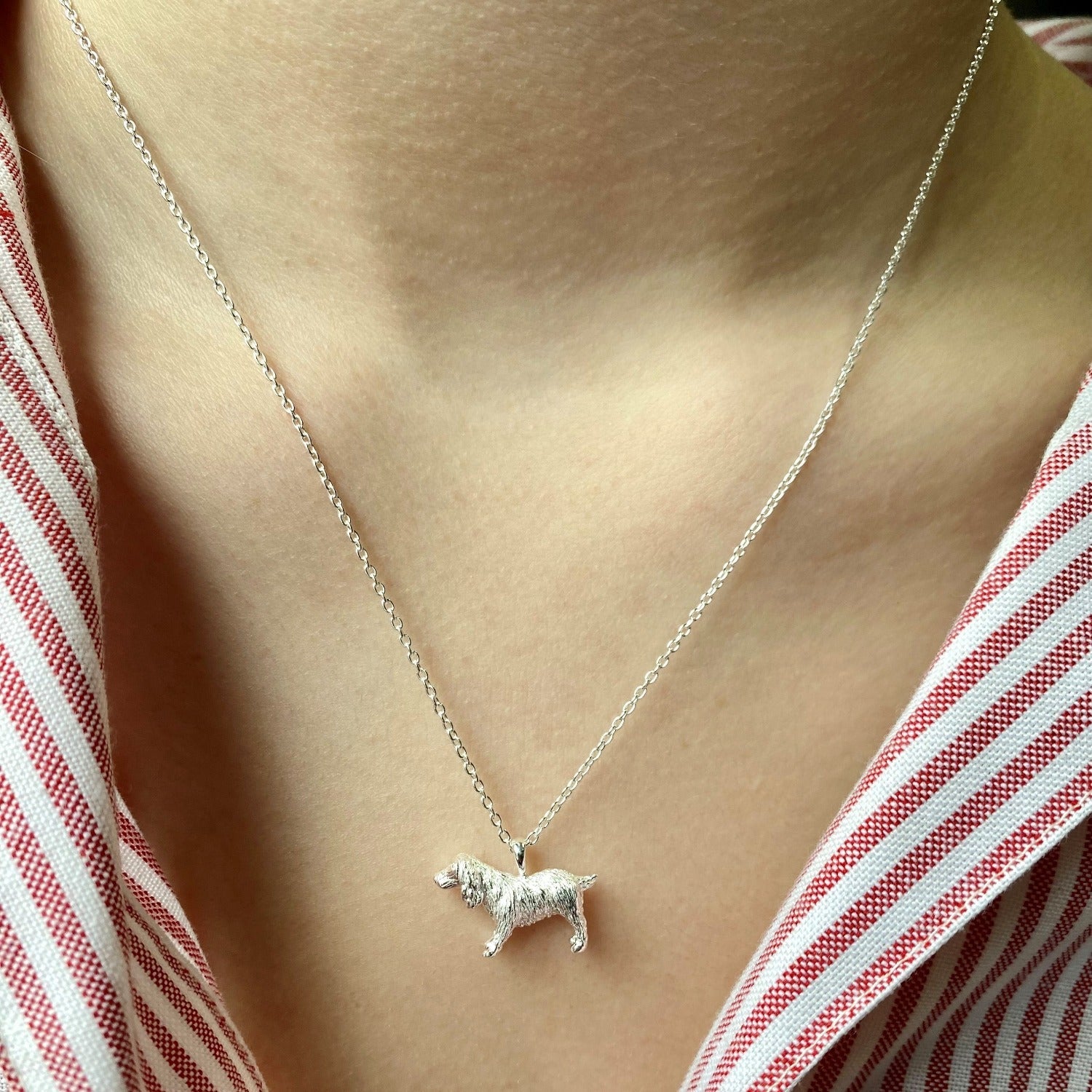 A Silver Spaniel Necklace hung on a silver chain and worn on a models neck.