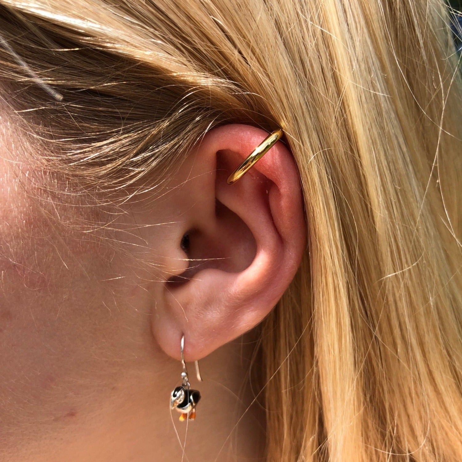 A single simple ear cuff, shown on a ladies ear.