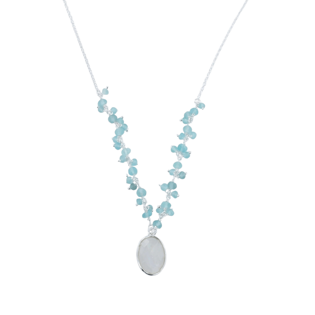 A silver chain necklace with an oval shaped moonstone hanging from the centre of the chain. Small Aqua chalcedony stones sit in clusters up either side of the chain.