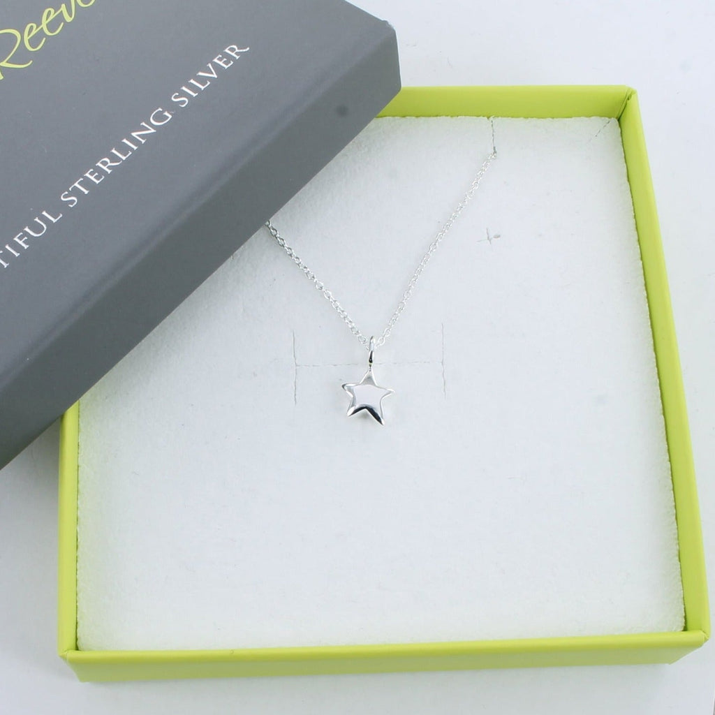 A silver star pendant hung on a silver chain and shown in a Reeves & Reeves grey and green branded gift.