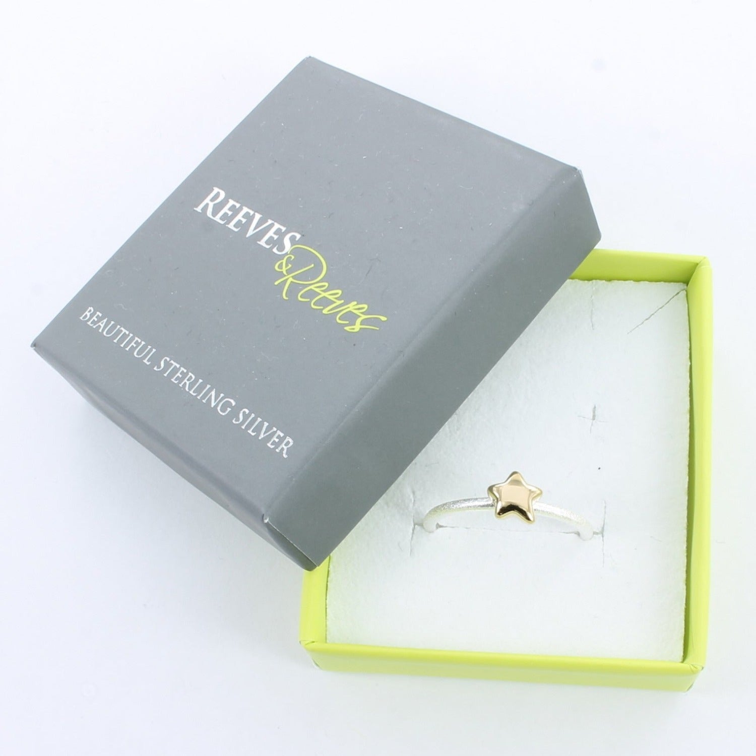 Silver Starlight Ring with a silver band and gold plated star, shown in a Reeves & Reeves grey and green branded gift box.