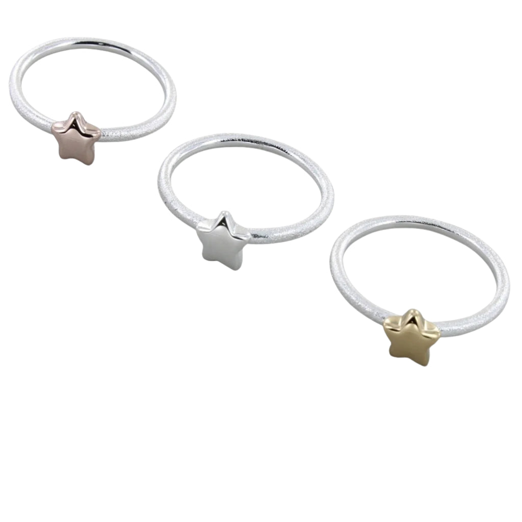 Three silver banded matt rings, one with a silver star, one with a yellow gold plated star and the other a rose gold plated star.