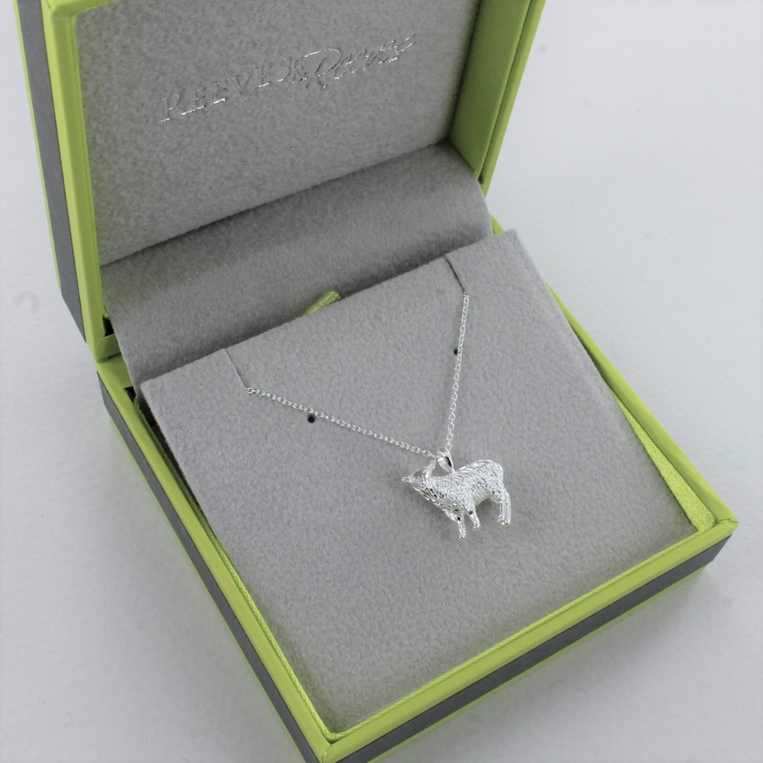 Sterling Silver Sheep Pendant, hanging on a silver adjustable chain and shown in a Reeves & Reeves grey and green branded gift box.