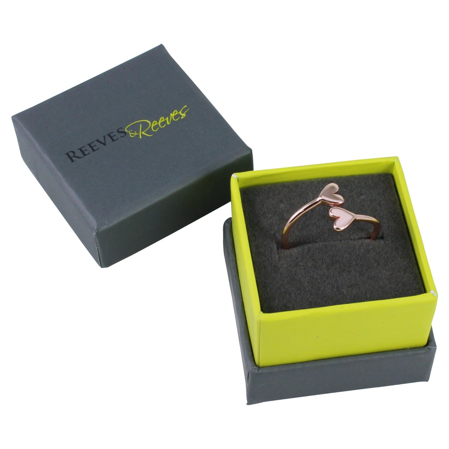 A rose gold plated adjustable ring with heart detail at each end of the band, shown in a Reeves & Reeves grey and green branded gift box.