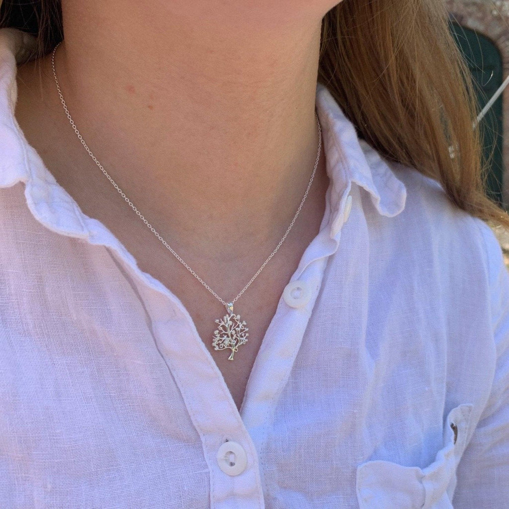 A sterling silver nut tree pendant hanging on a silver adjustable chain and worn on a model.