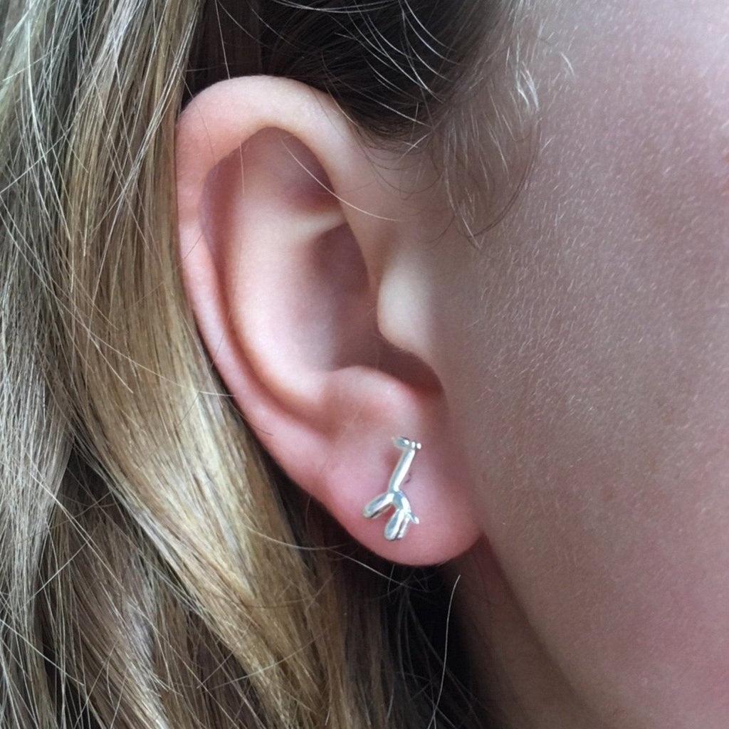 A sterling silver giraffe stud earring, in a balloon style and shown in a ladies ear.