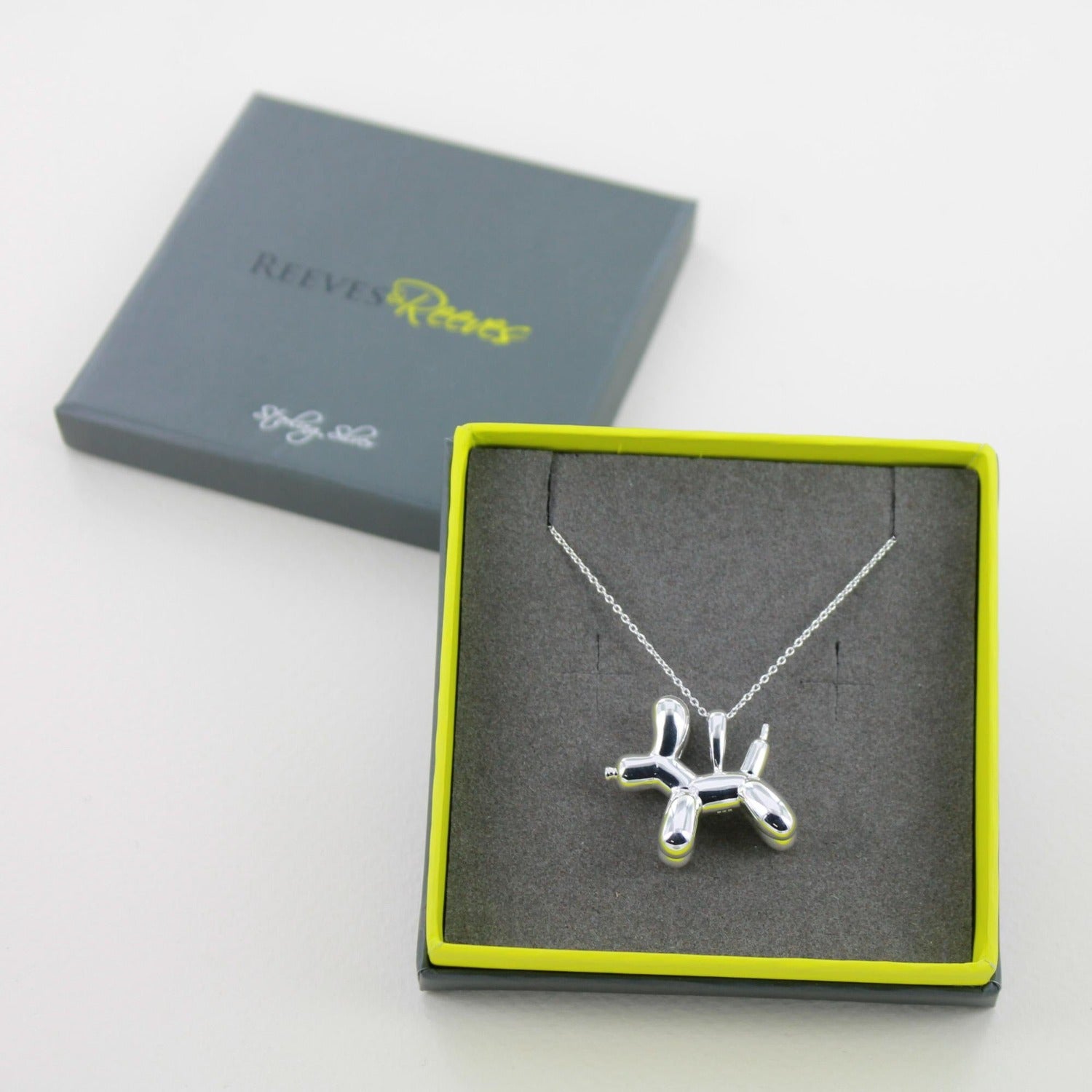 Sterling Silver Supersize Balloon Dog Necklace, hung on a silver chain and shown in a grey and green branded Reeves & Reeves gift box.