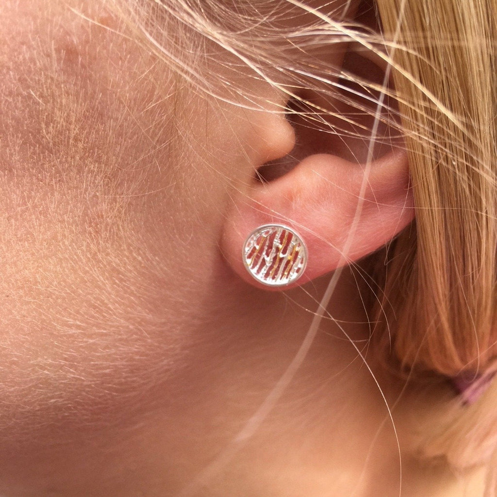 A pair of silver birch earrings, with 18ct gold plated detail and shown in a ladies ear.