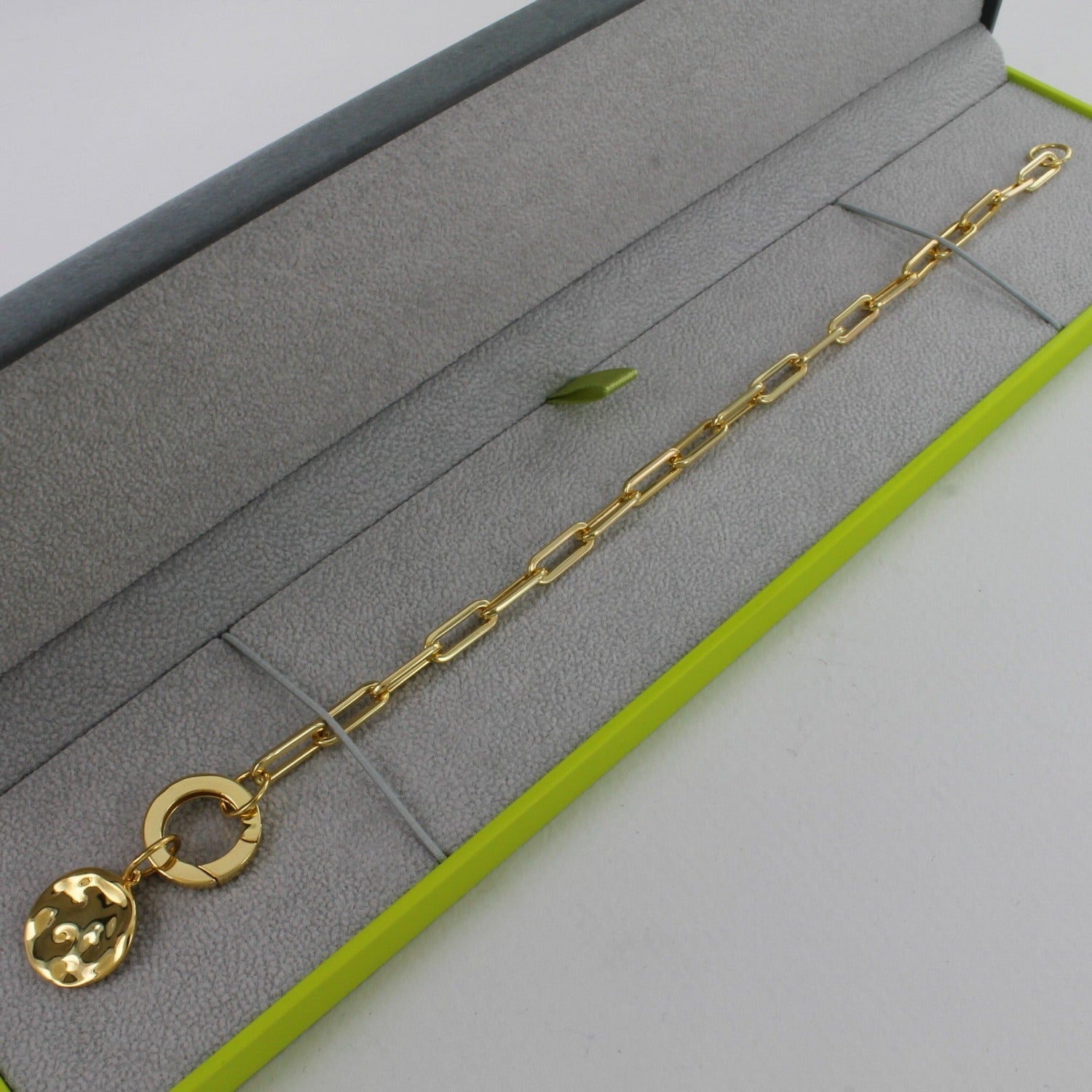 A gold plated paperclip style chain bracelet, shown in a Reeves & Reeves grey and green branded gift box.