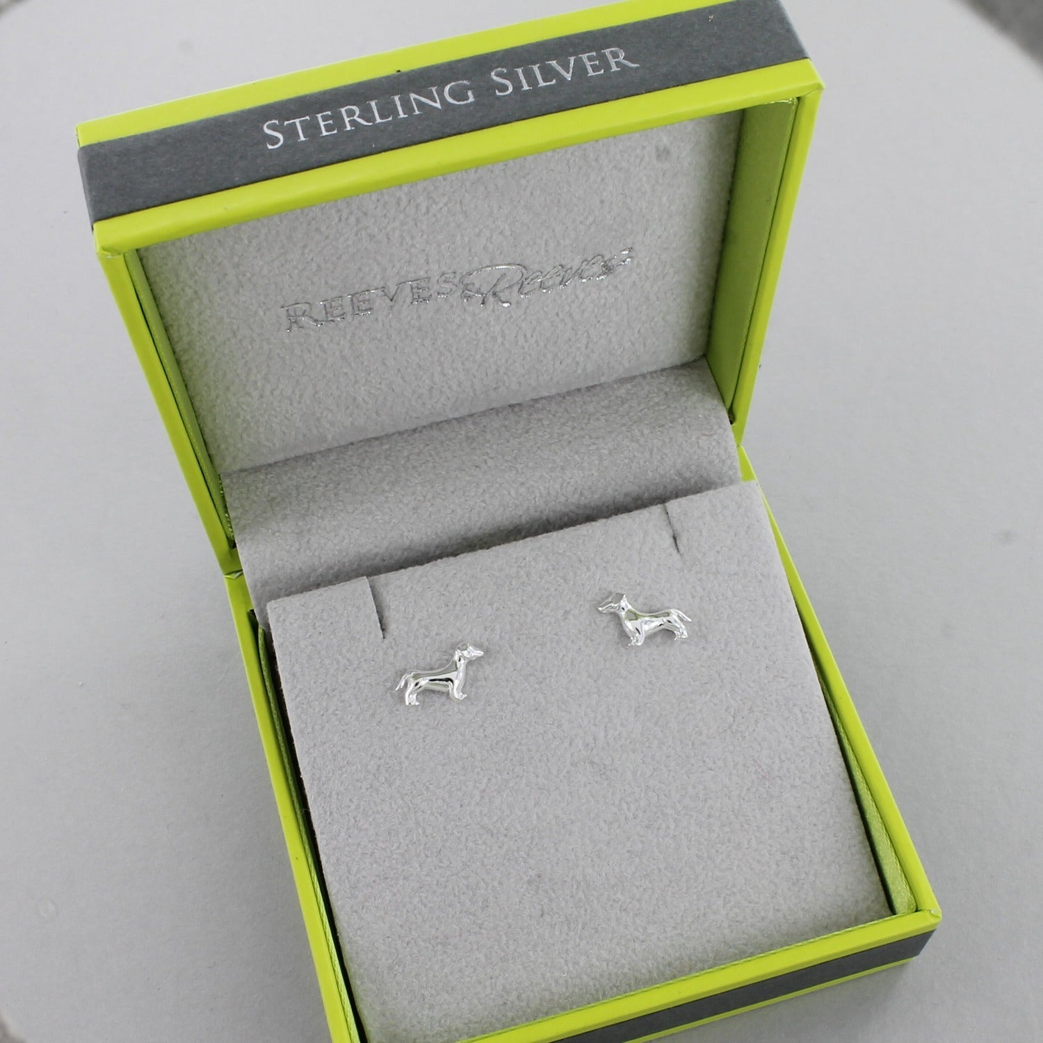 A pair of Sterling Silver Dachshund Stud Earrings shown in a Reeves & Reeves gift box.