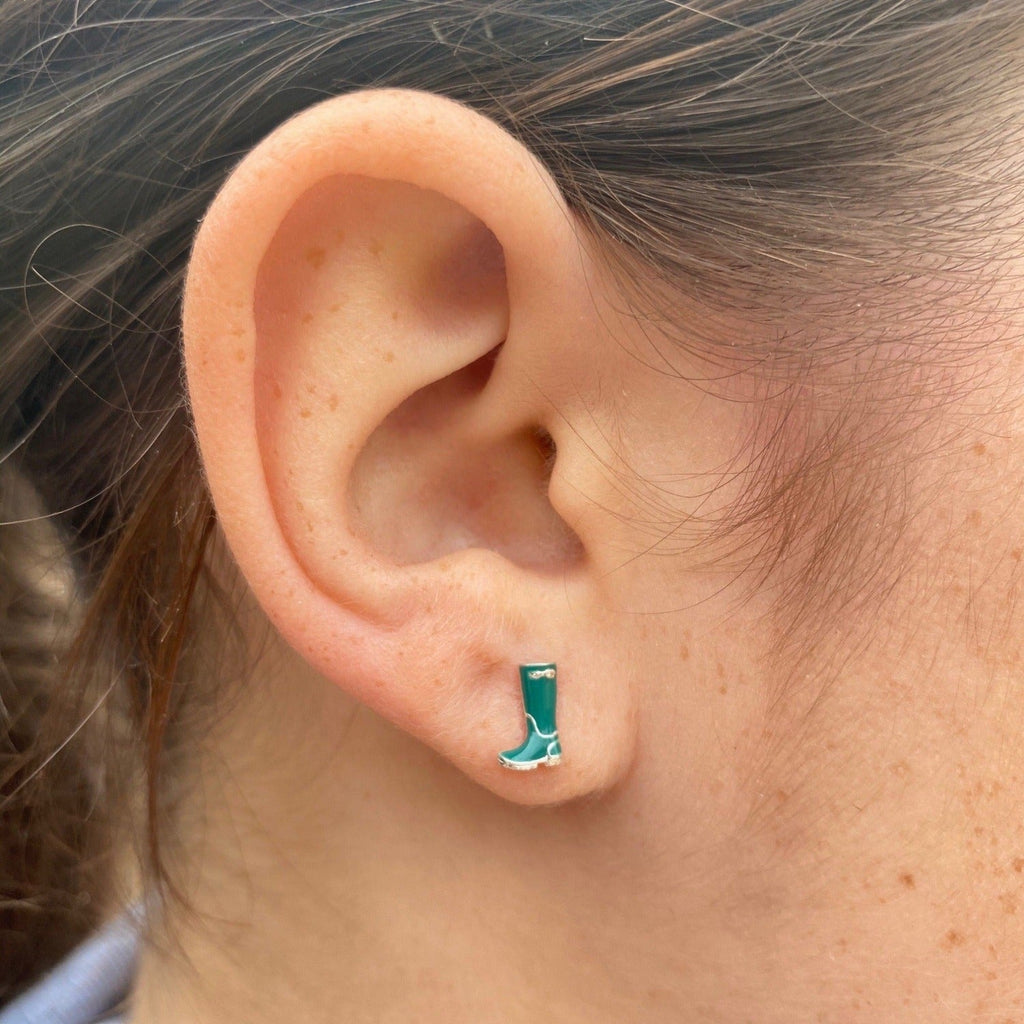 A green enamel Wellington Boot stud earring, in sterling silver and shown in a ladies ear.