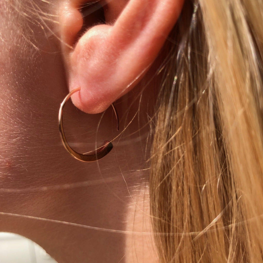 A pair of 18ct gold plated hoop earrings, worn in a ladies ear and bent round in a farrier nail shape.