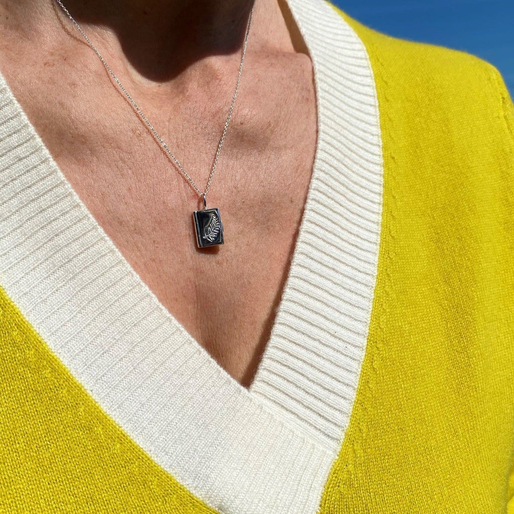 A sterling silver book locket which opens and a feather etched on the front. Hung on a silver adjustable chain and worn on a ladies neck.