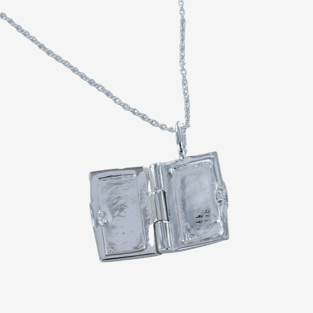 A sterling silver book locket, shown open and hung on a silver chain.