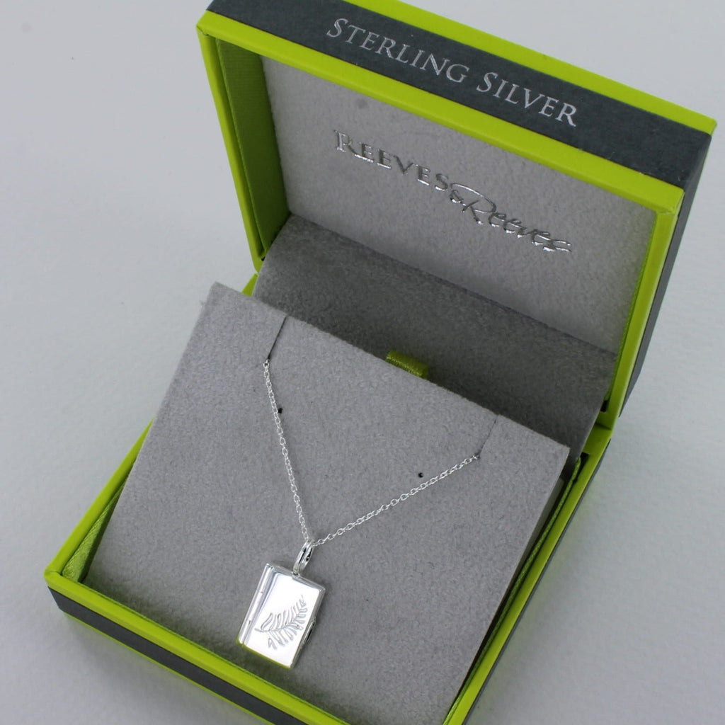 A sterling silver book locket with a feather etched on the front and hung on a silver chain. Shown in a Reeves & Reeves grey and green branded gift box.