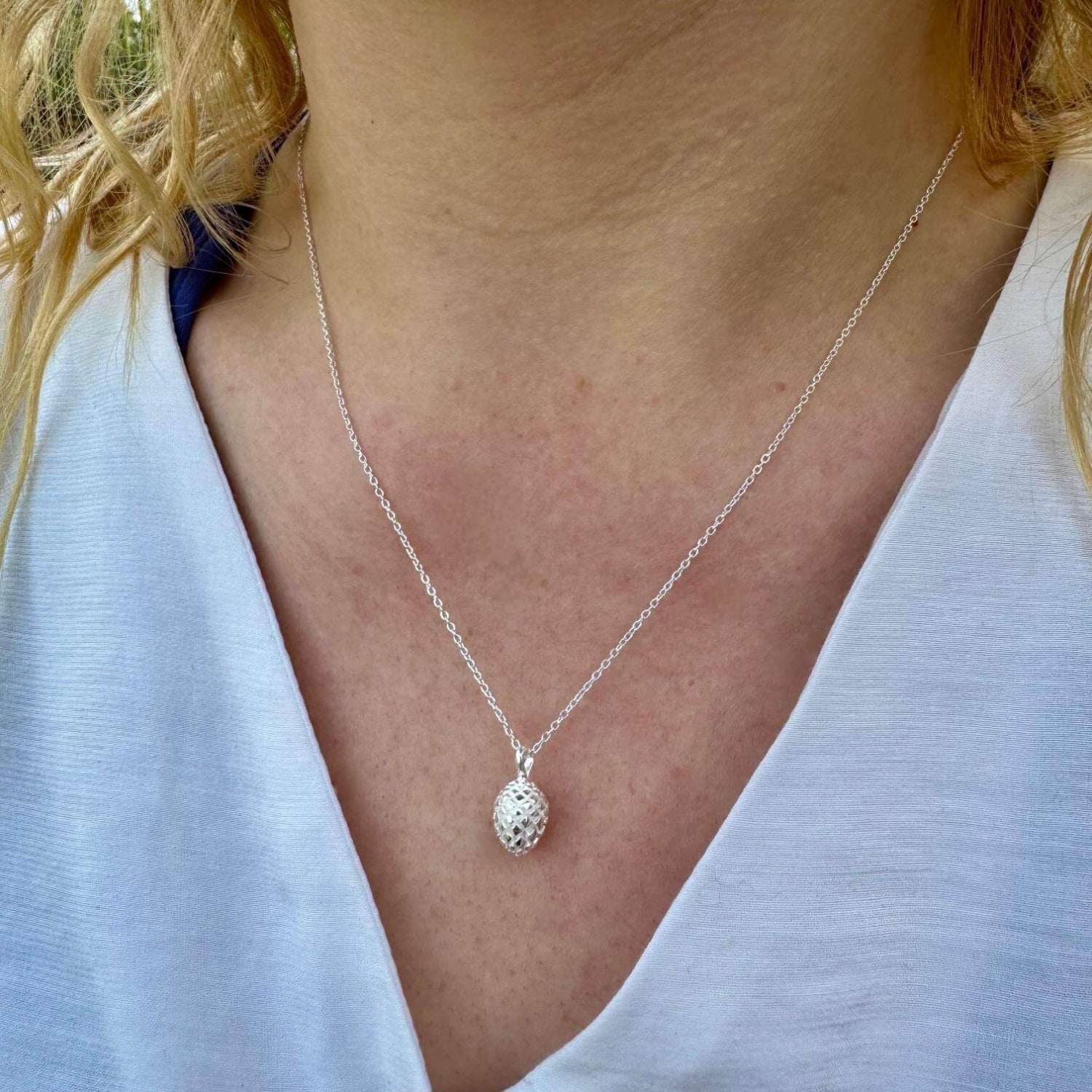 A sterling silver Fir cone Necklace, hung on a silver adjustable chain and worn on a model.
