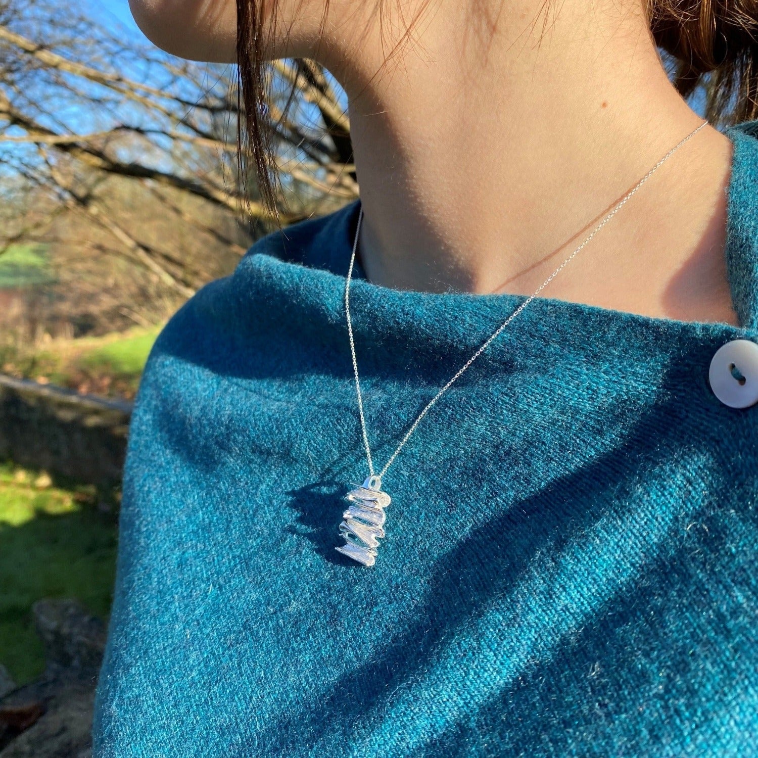A sterling silver flaky pendant, hung on a silver chain and worn on a model.