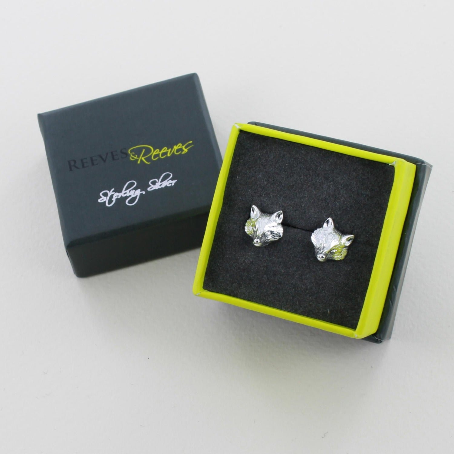 A pair of sterling silver Fox Head Stud Earrings, shown in a Reeves & Reeves grey and green gift box.