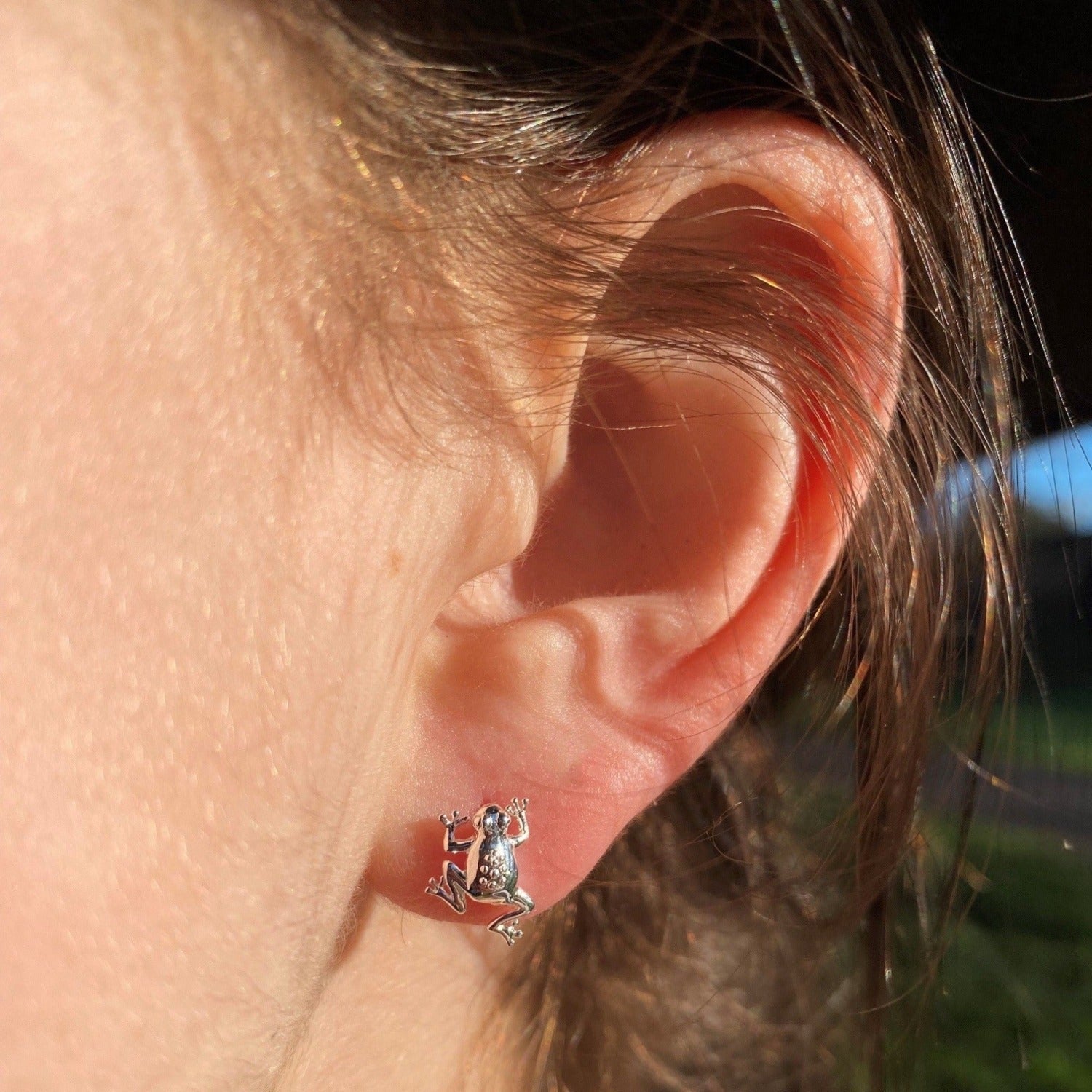 A pair of Sterling Silver Frog Stud Earrings, shown in a ladies ear.