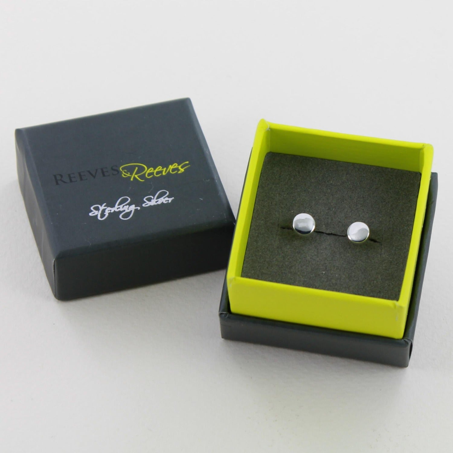 A pair of sterling silver round studs, shown in a Reeves & Reeves gift box.