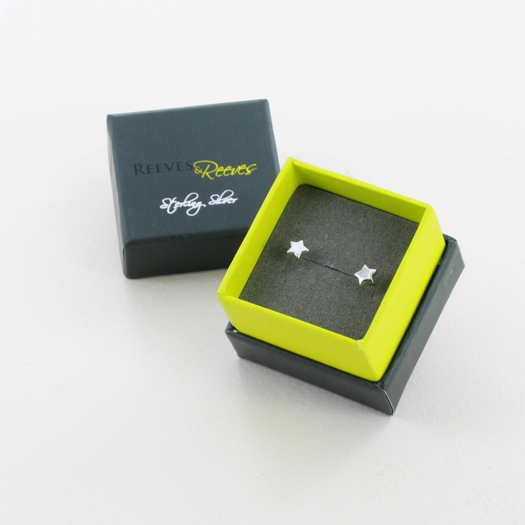 A pair of sterling silver star studs, shown in a Reeves & Reeves grey and green gift box.