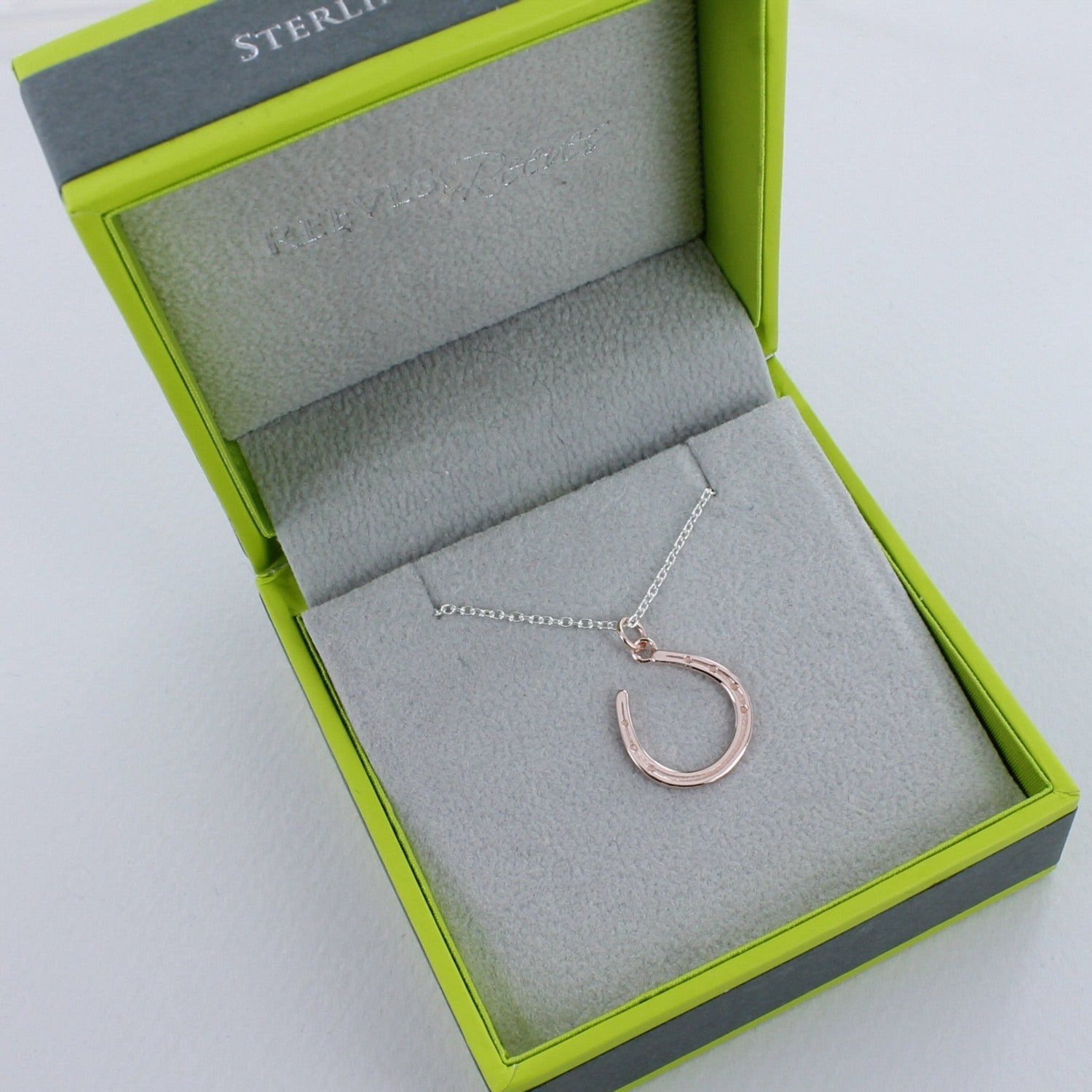 A Sterling Silver with rose gold plating horseshoe necklace, on an adjustable silver chain. Shown in a Reeves & Reeves branded grey and green gift box.