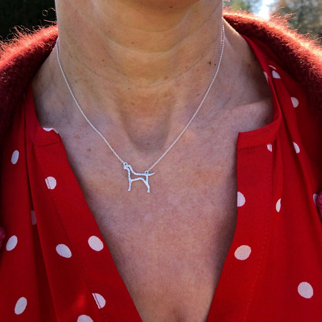 A sterling silver Hound silhouette with a hammered finish, hung centrally on a fine silver adjustable chain. Worn on a ladies neck.