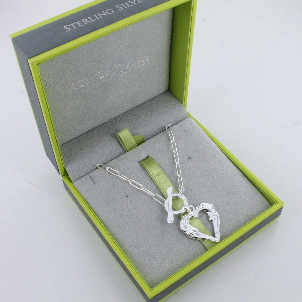 A sterling silver silhouette heart pendant hanging from a circular clasp with a t bar on a paperclip style chain and shown in a Reeves & Reeves gift box.