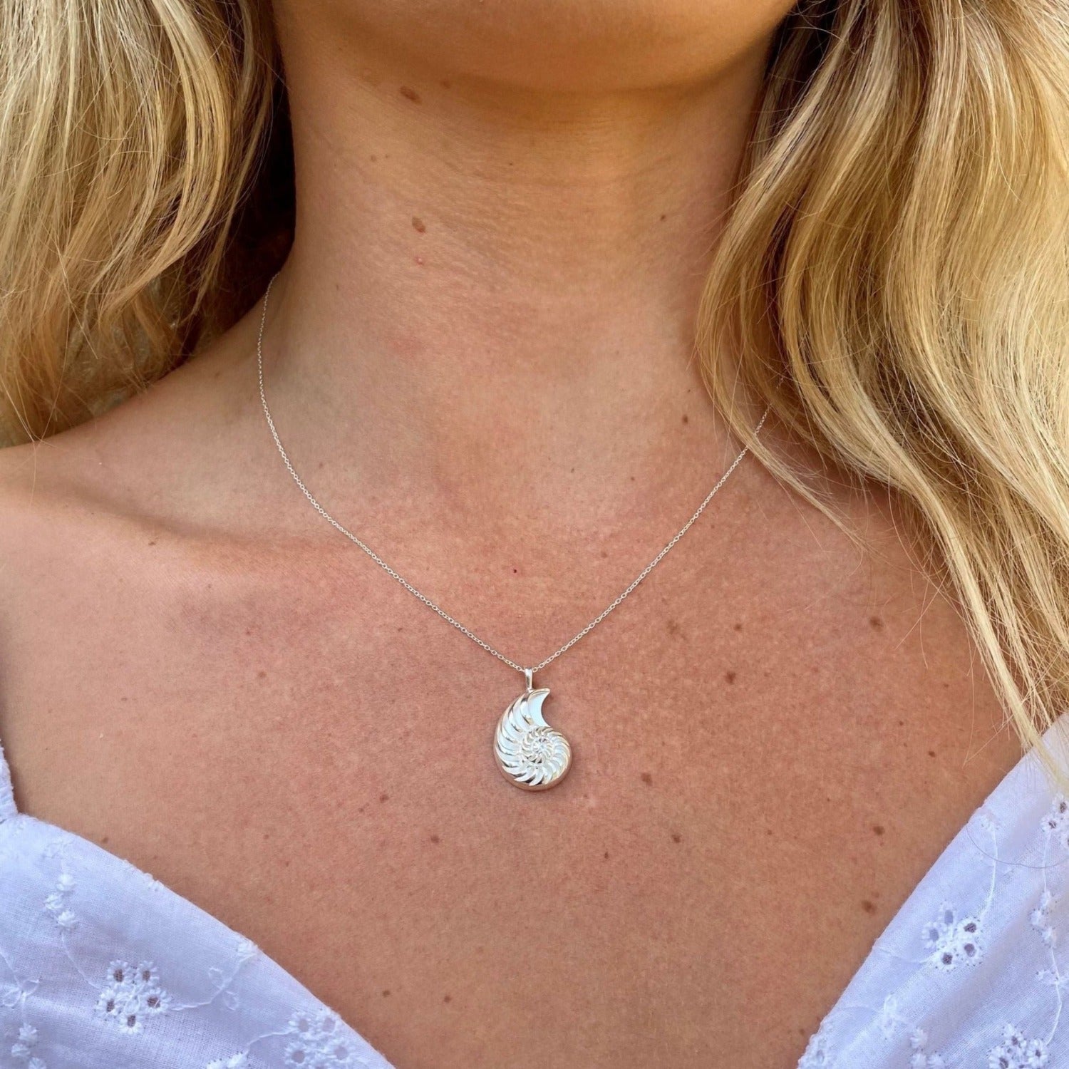 A large Jurassic Coast Ammonite Shell Pendant, on a silver chain and worn on a model.
