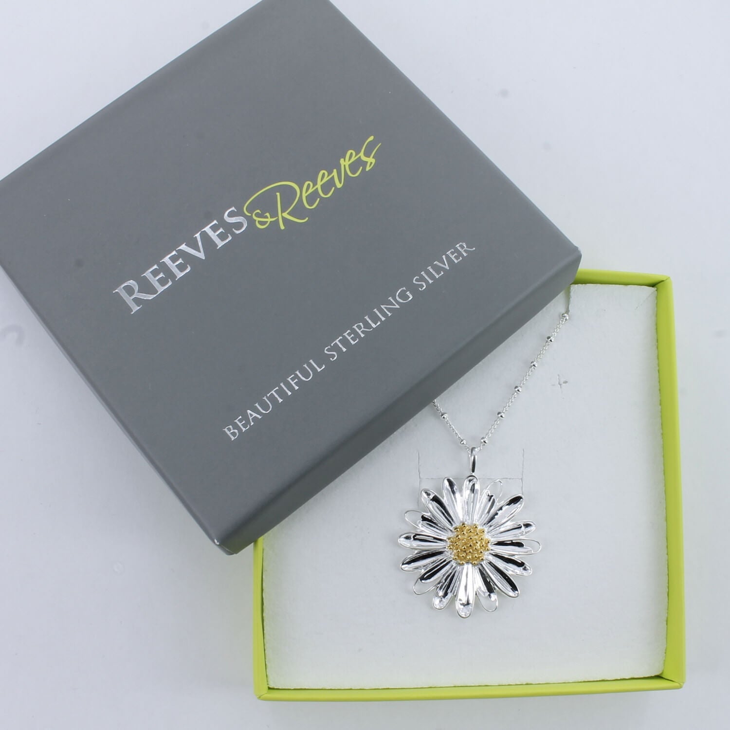 A sterling silver large daisy necklace, with an 18ct gold plate centre, hung on a silver beaded chain and shown in a Reeves & Reeves gift box.
