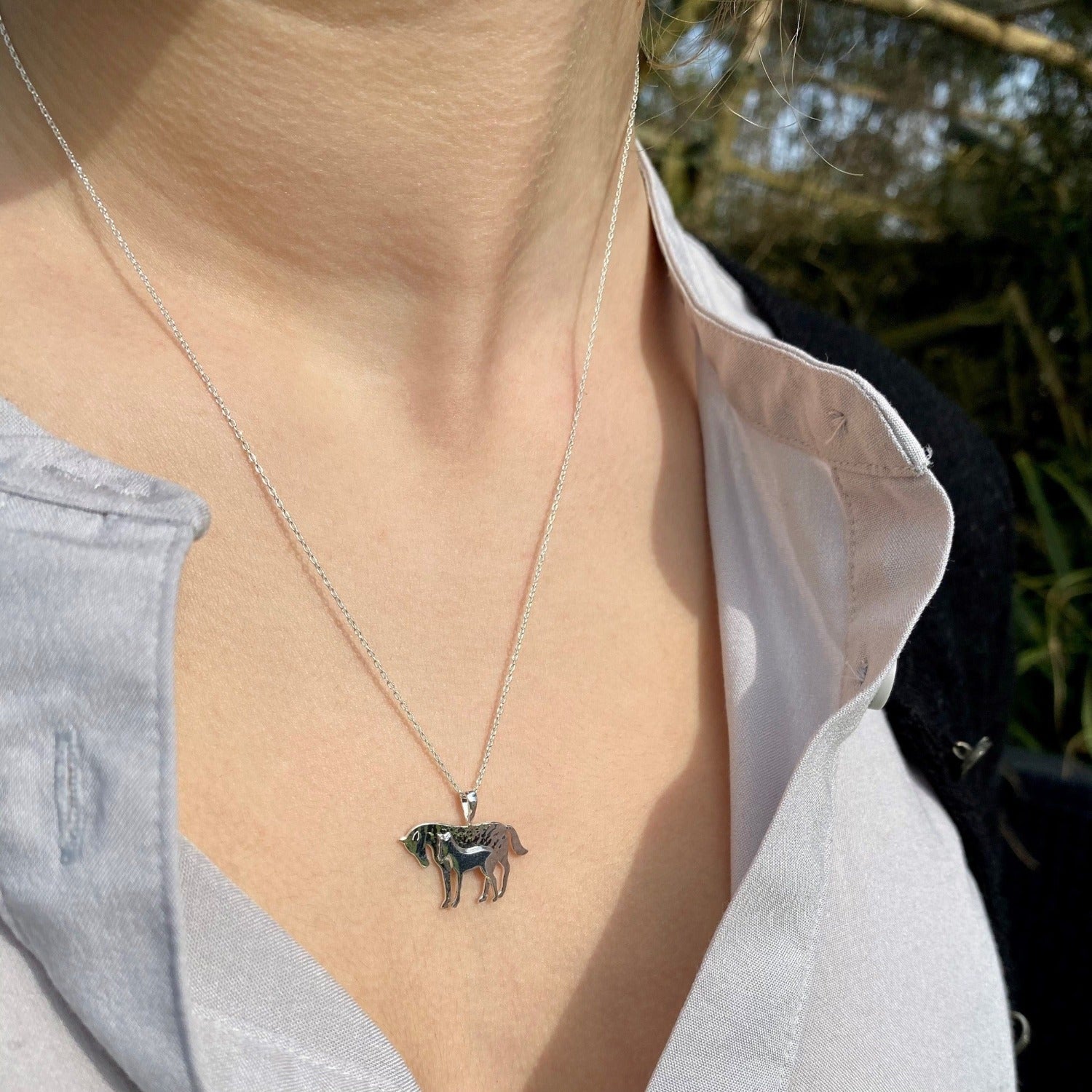 Silver Mare and Foal pendant, hammered finish on the mare and hung on a silver chain. Worn on a models neck.