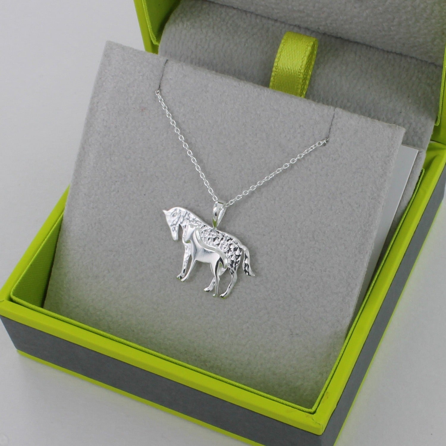 A silver Mare and Foal pendant on a silver chain and shown in a Reeves & Reeves grey and green gift box.