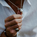 A sterling silver Wildebeest pendant, with black ruthenium horns and shown on a chain, worn on a man.