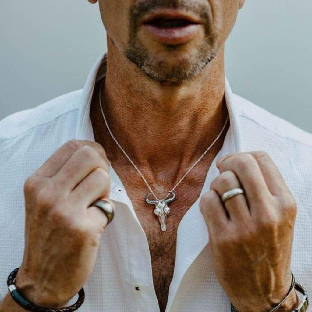 A sterling silver Wildebeest Pendant Necklace worn on a rope style chain on a man's neck.