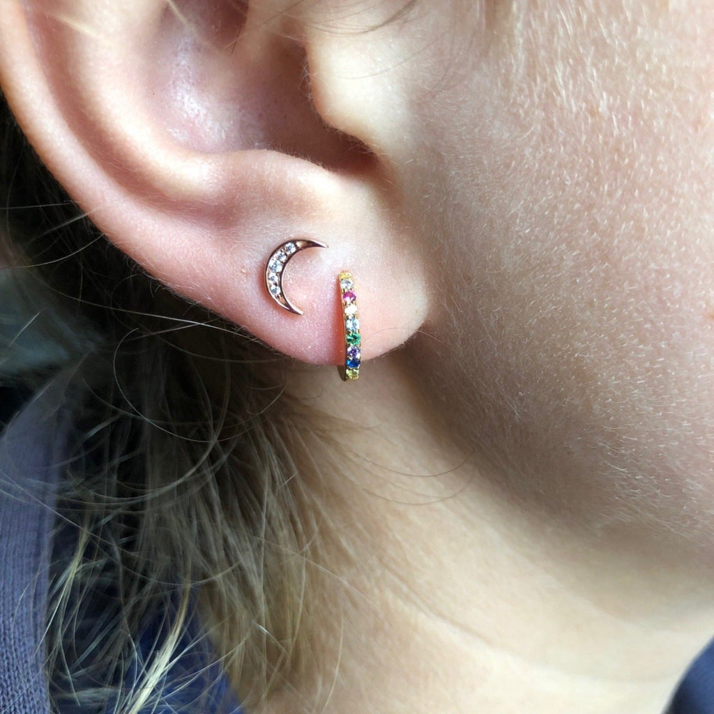 A pair of sterling silver huggies with 18ct gold plating and filled with cubic zirconia stones. Shown in a ladies ear.