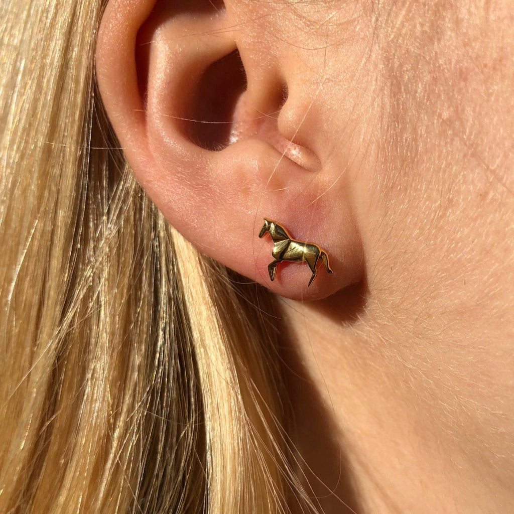 A sterling silver horse stud earring with 18ct gold plate in an origami style. Shown in a models ear.