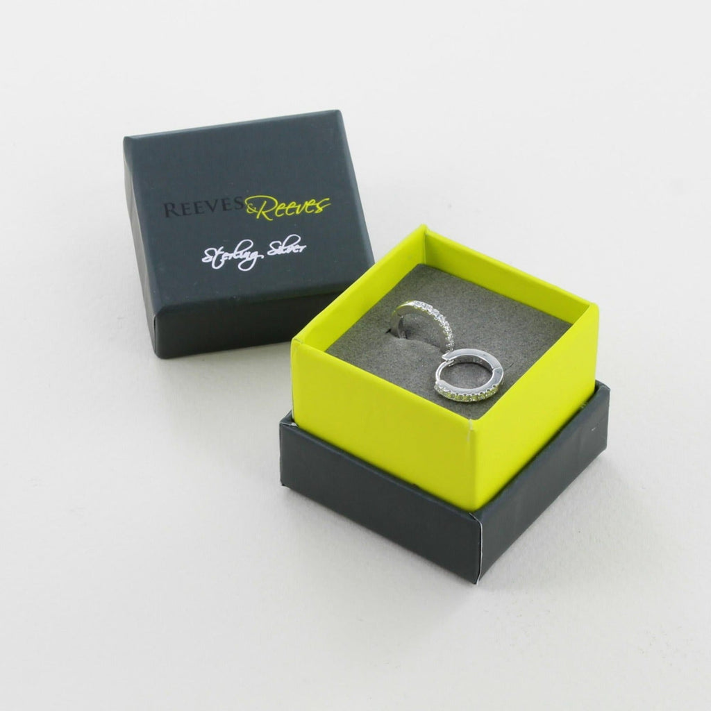 A pair of sterling silver huggies with cubic zirconia stones, shown in a Reeves & Reeves grey and green gift box.