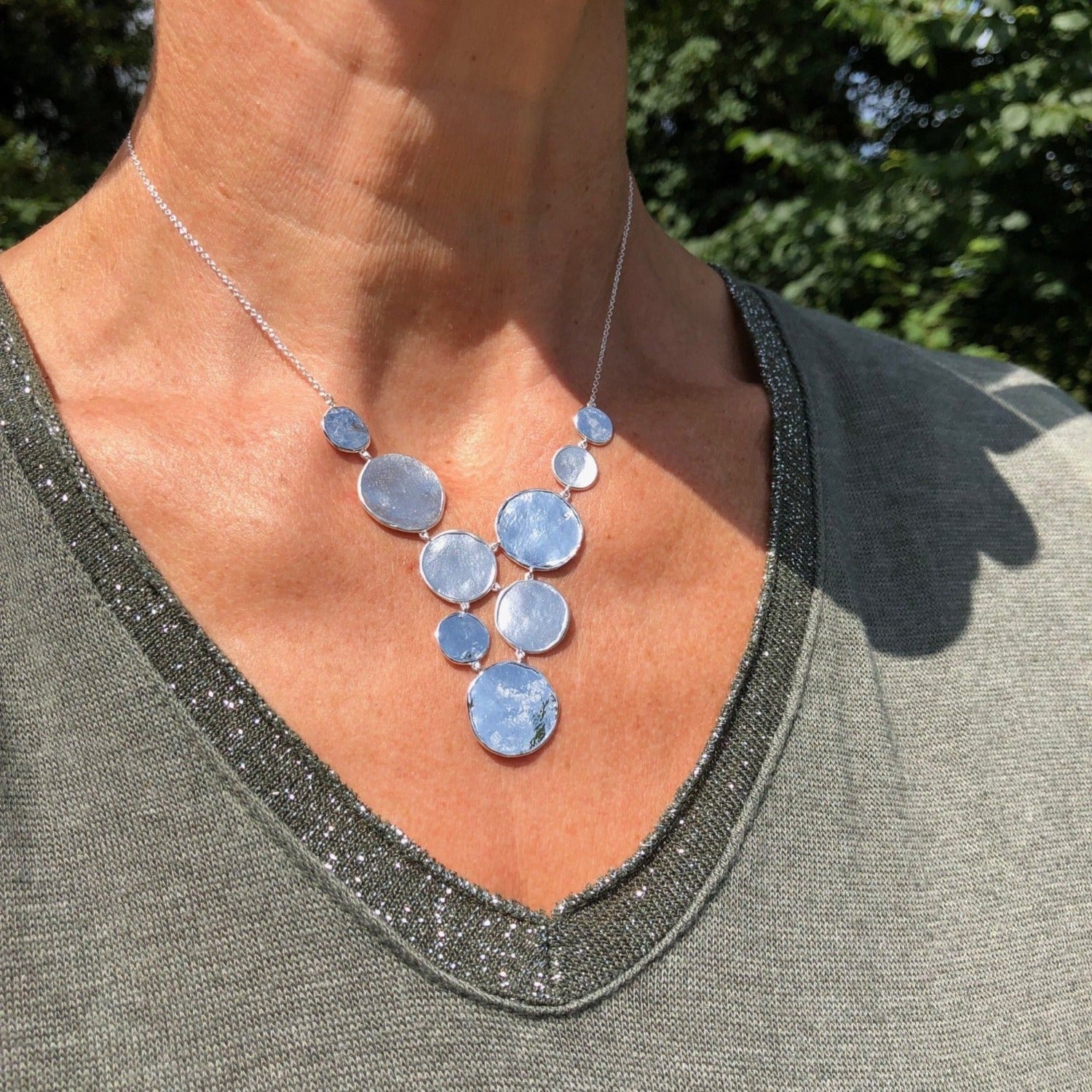Sterling Silver high shine discs, set in a waterfall style design and hung on a silver chain which is worn on a model.