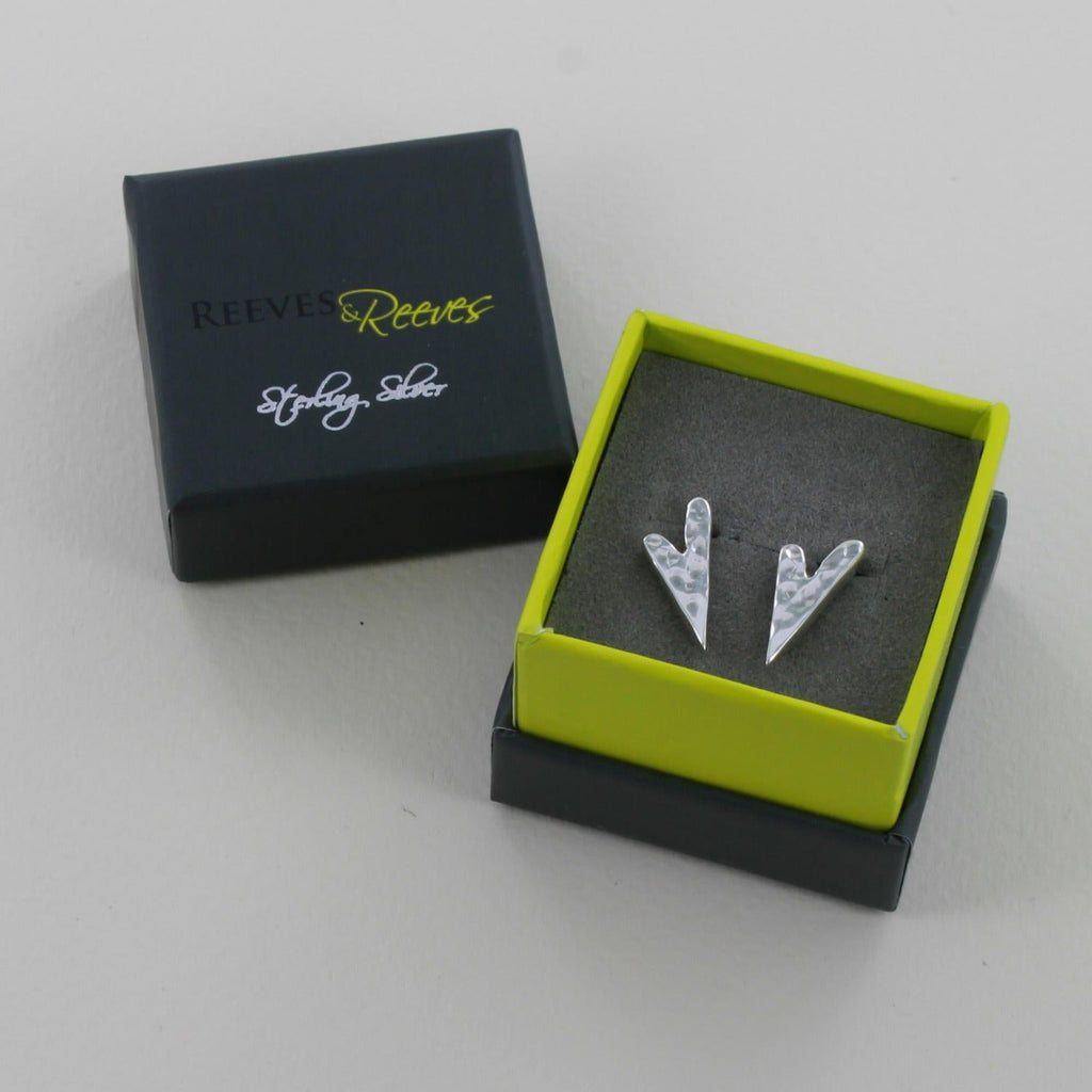 A pair of irregular heart stud earrings with a hammered finish. Shown in a Reeves & Reeves gift box.
