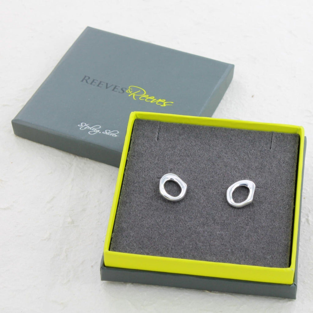 A pair of sterling silver stud earrings in an irregular circular shape and shown in a Reeves & Reeves gift box.