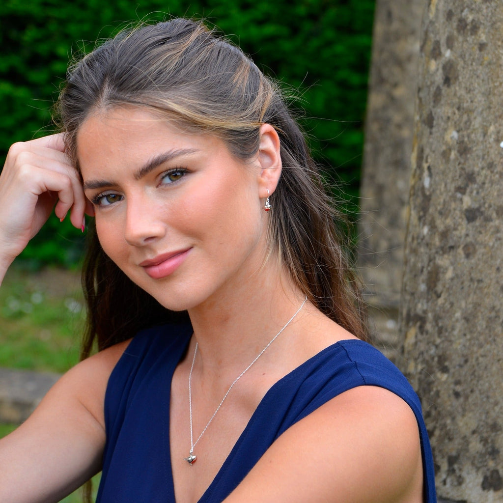 A sterling silver Robin Earring on a silver hook and shown with red enamel detail on its breast. Worn on a model with the matching necklace.