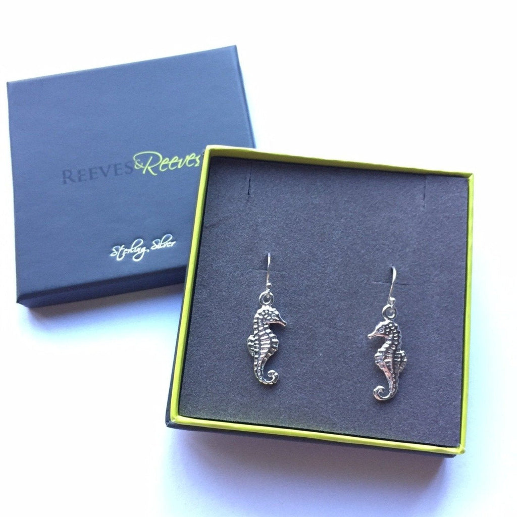 A pair of sterling silver Seahorse Earrings on silver hooks, shown in a Reeves & Reeves gift box.