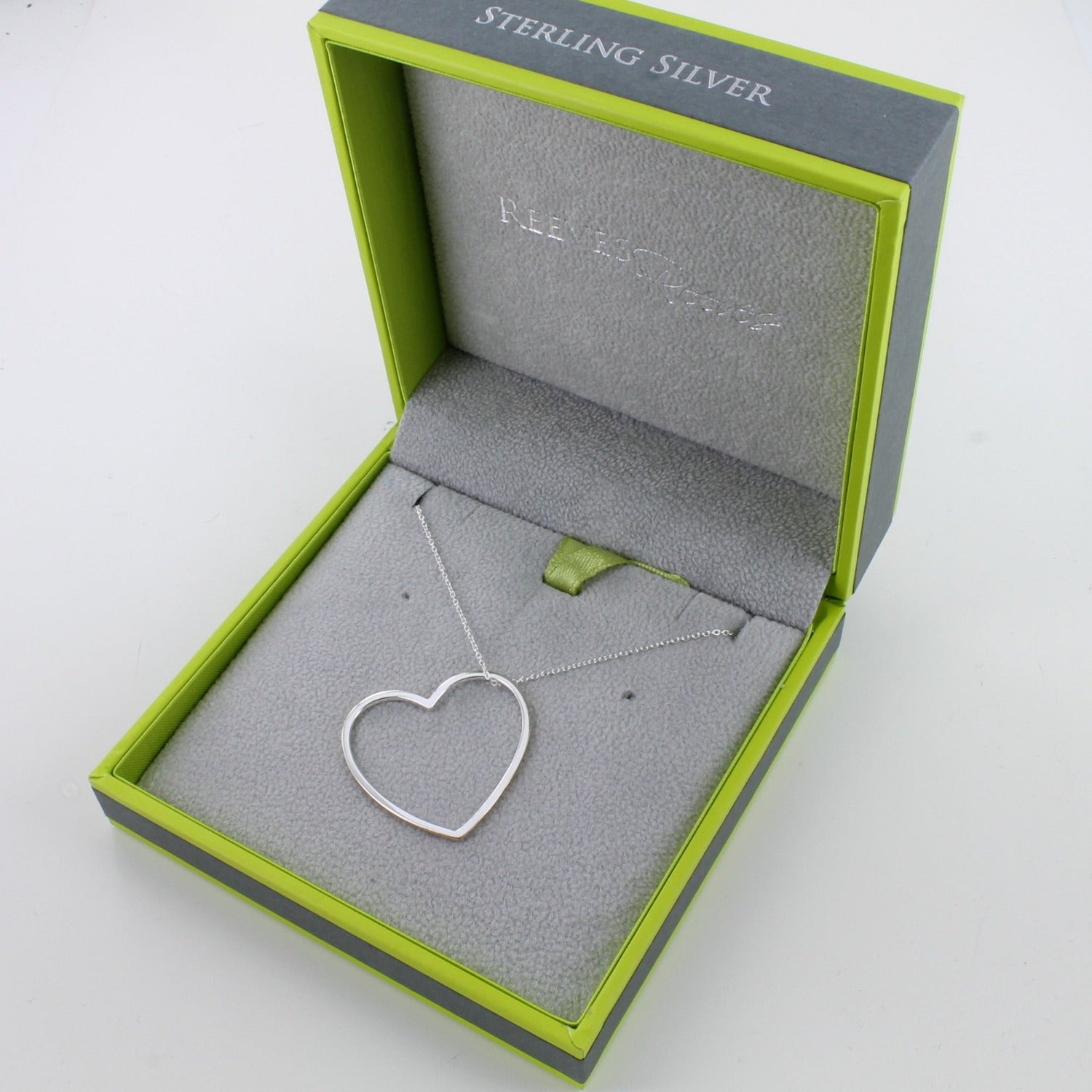 A Sterling Silver Heart Silhouette Pendant with gold plated edges and hung on a silver chain. Shown in a Reeves & Reeves grey and green branded gift box.
