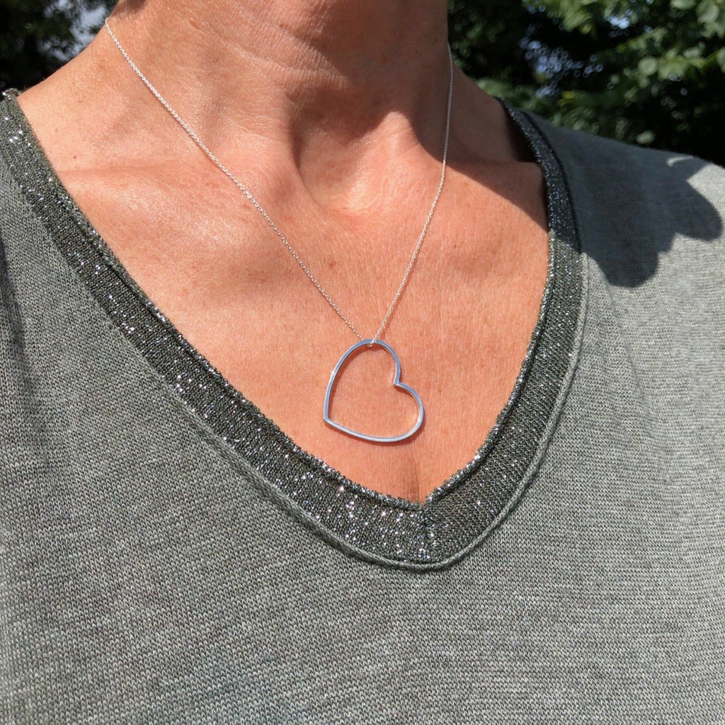Sterling Silver Heart Silhouette with gold plated edges, hung on a silver chain worn on a models neck.