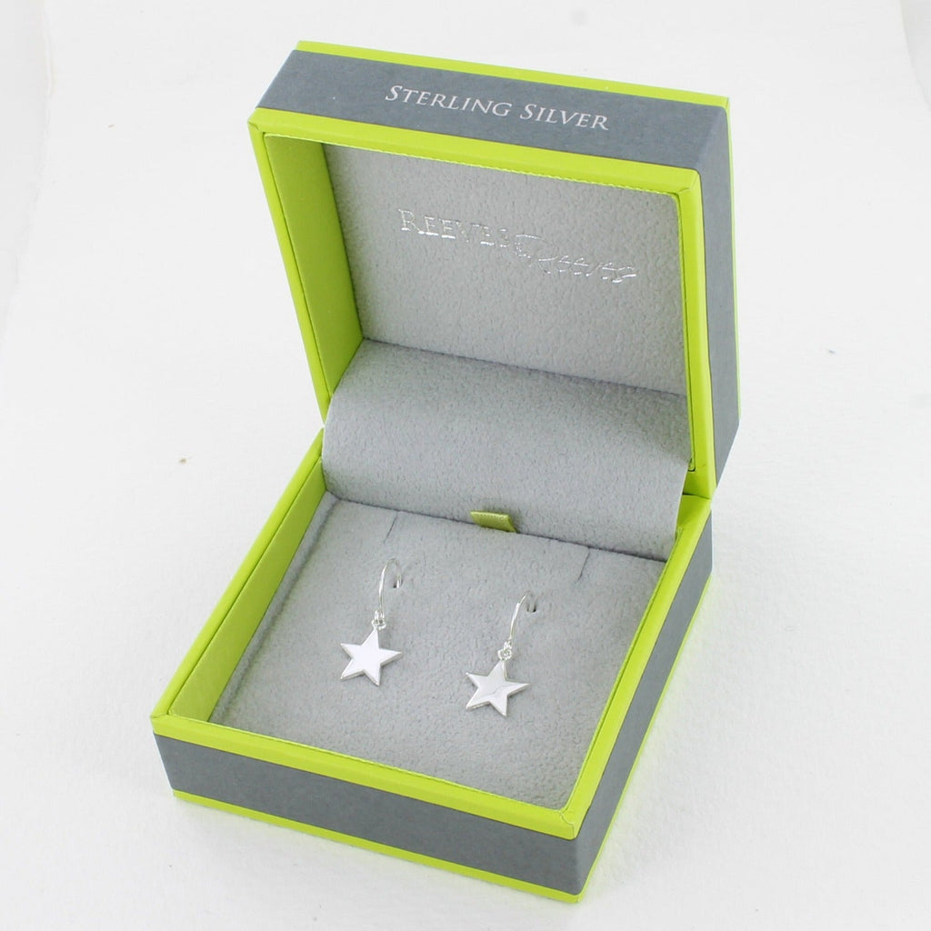 A pair of sterling silver drop earrings with flat star charms hanging from silver hooks and shown in a Reeves & Reeves gift box.