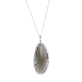 An oval smokey quartz semi precious stone, set in sterling silver and hung on a silver adjustable chain.